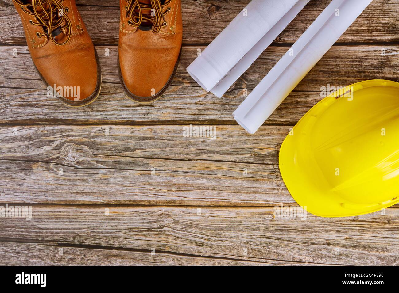 Arquitecto trabajando con planos ver conjunto de ropa de trabajo de  protección botas de trabajo en casco amarillo en la oficina Fotografía de  stock - Alamy
