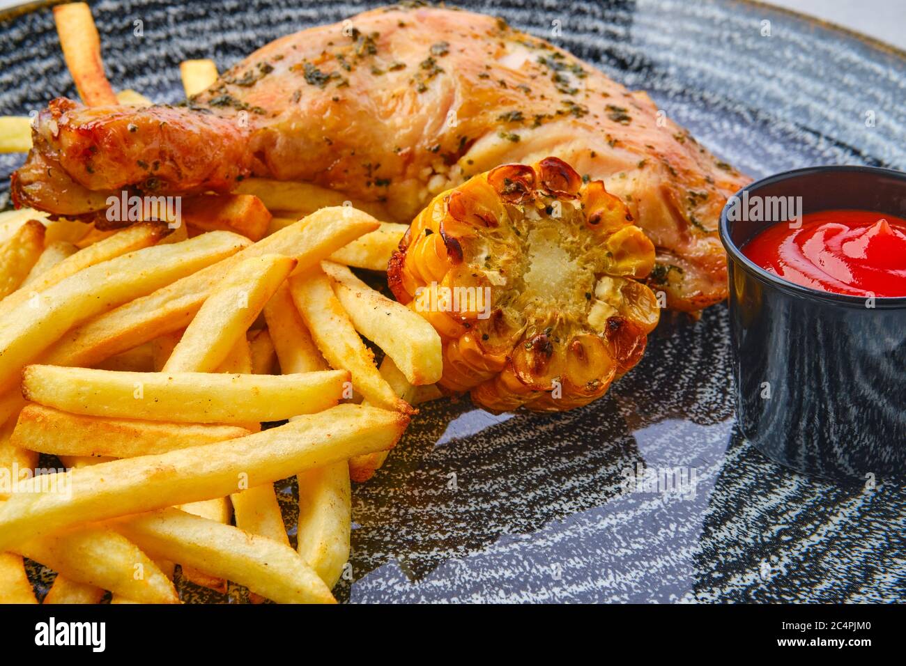 Vista de cerca del muslo de pollo al horno con patatas fritas, maíz a la  parrilla y ketchup en mesa de madera oscura Fotografía de stock - Alamy