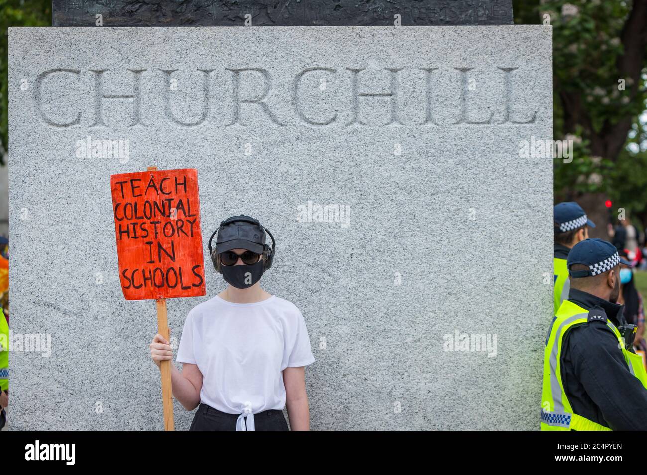Protestor pidiendo que se enseñe el colonialismo en las escuelas bajo la estatua de Churchill en una protesta de la materia de vidas negras en Londres Foto de stock