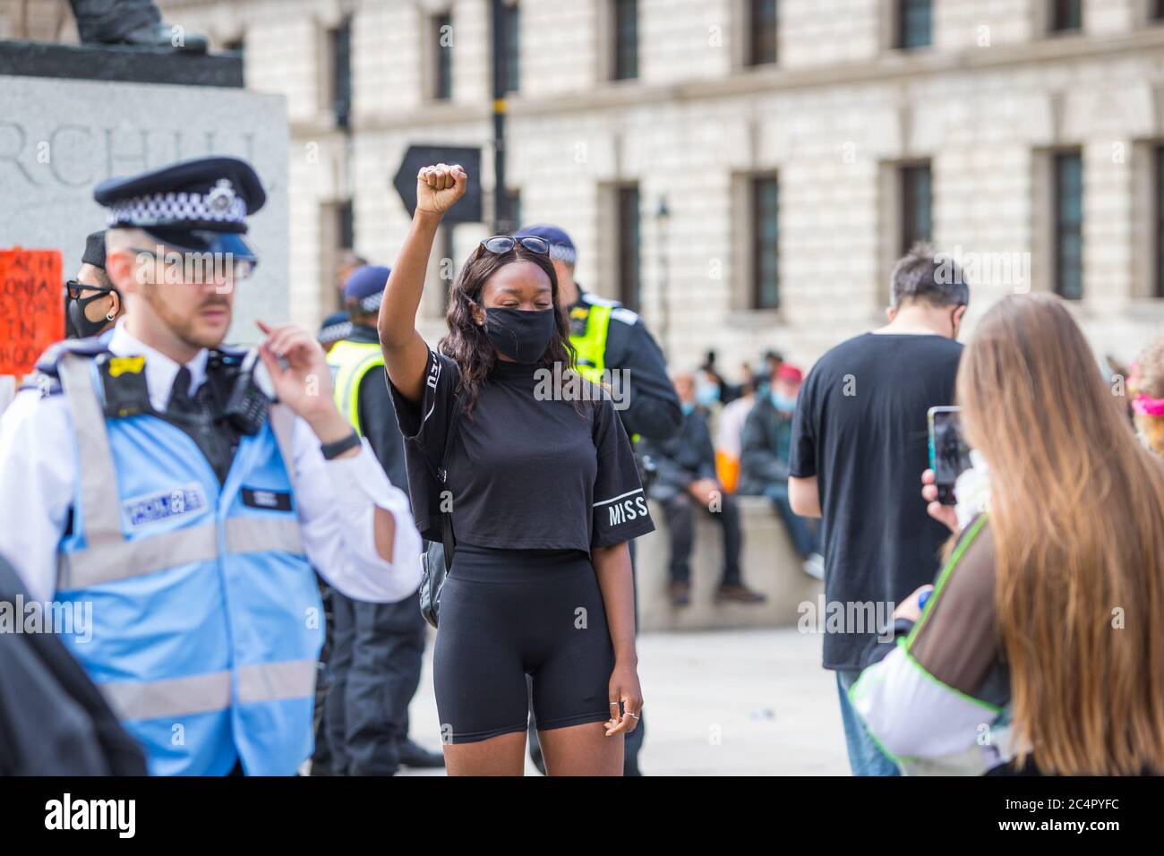 Una joven protestera tiene su foto tomada por un amigo frente a la estatua de Churchill en una protesta de la materia Black Lives en Londres Foto de stock