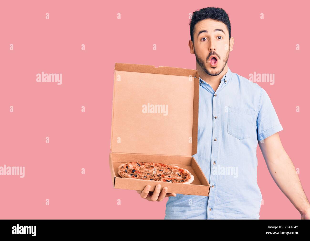 Joven hispano sosteniendo la caja de pizza de reparto asustada y asombrada  con boca abierta para sorpresa, cara de incredulidad Fotografía de stock -  Alamy