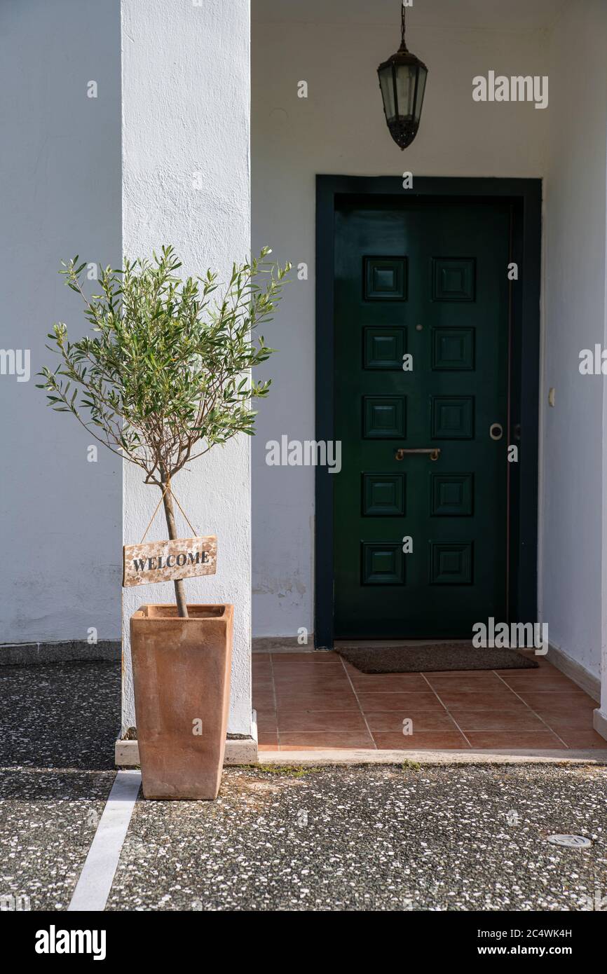 Cartel de bienvenida de madera rústica colgado en un olivo frente a una  casa de puertas verdes en verano Fotografía de stock - Alamy