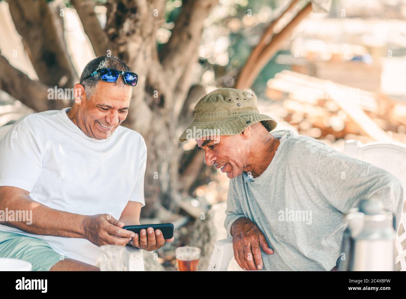 Dos hombres mayores felices niños amigos de los boomers Diversión Use el teléfono inteligente. Estilo de vida activo y saludable. Foto de stock