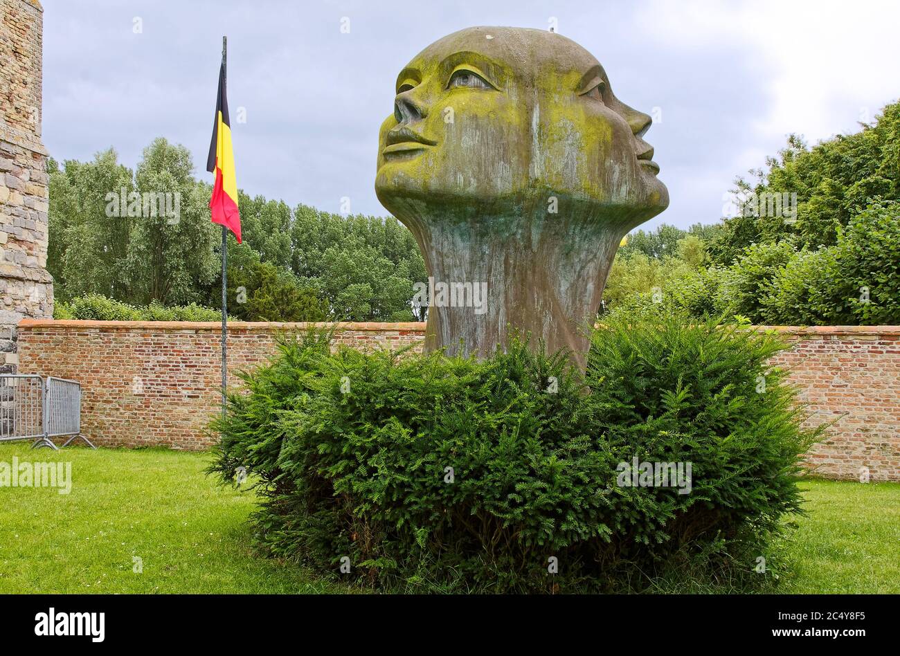 Mirada de la Luz, estatua de 2 cabezas, Blik van Licht, escultor Charles Delporte, arte público, al aire libre, vegetación, bandera belga, pared de ladrillo, Europa, Damme; Foto de stock