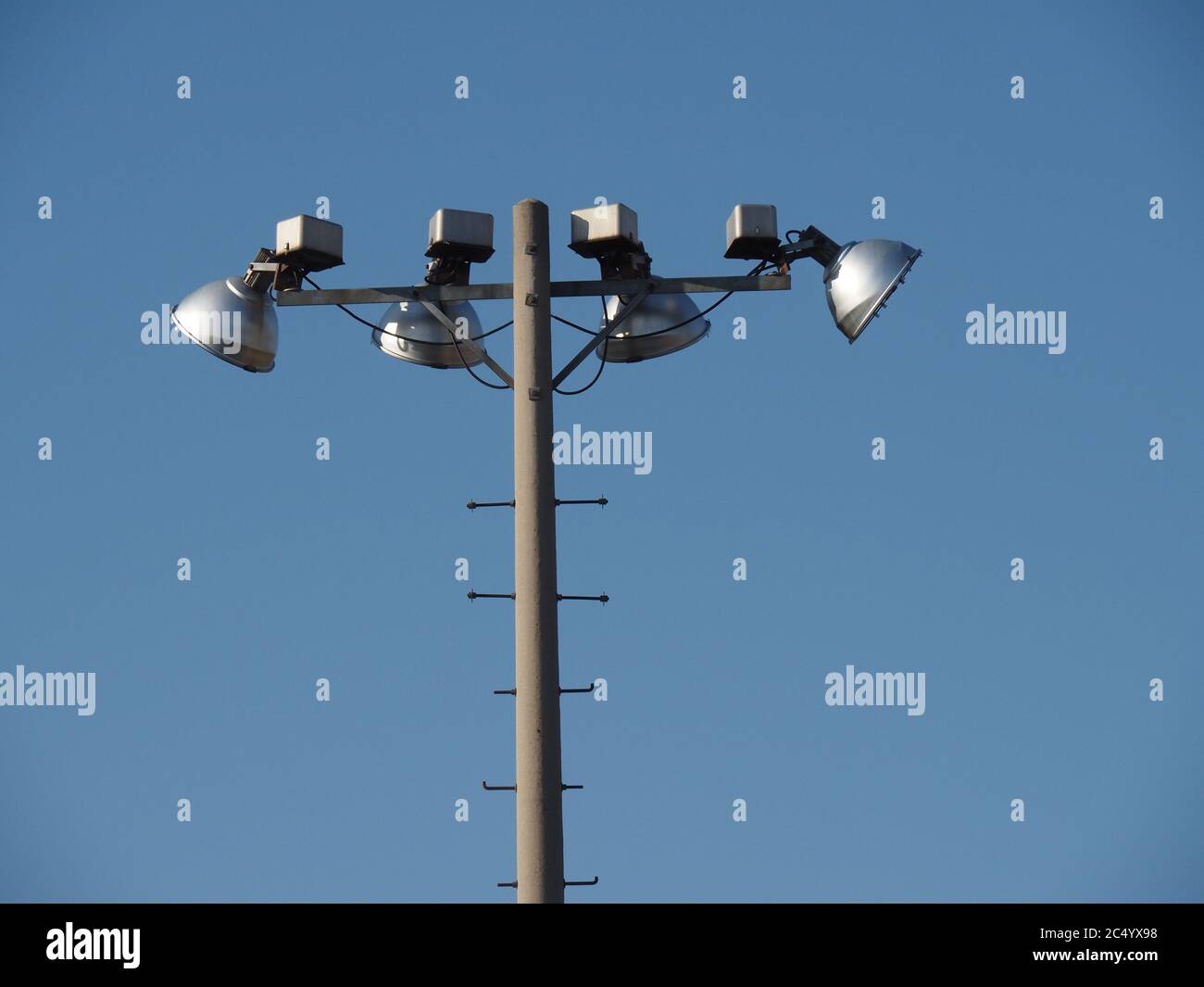 cuatro luces de vapor de mercurio en el estadio en la parte superior de un  poste de concreto contra un cielo azul Fotografía de stock - Alamy