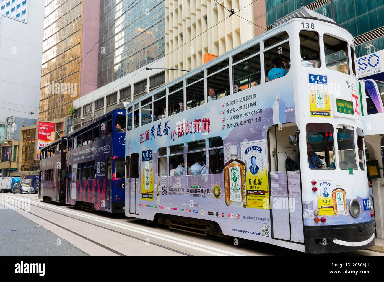 Tranvías eléctricos en el Distrito Central. La isla de Hong Kong está cubierta de anuncios coloridos y rodeada de rascacielos. Foto de stock