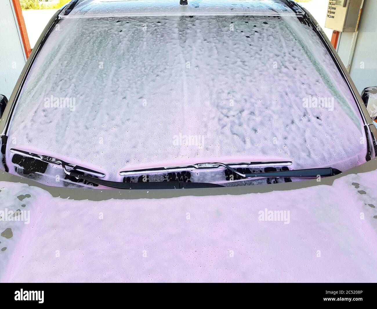 Primer plano del parabrisas delantero con escobillas de limpiaparabrisas  cubiertas una espuma activa de lavado rosa para limpiar un coche en el auto-servicio  de lavado de coches Fotografía de stock - Alamy