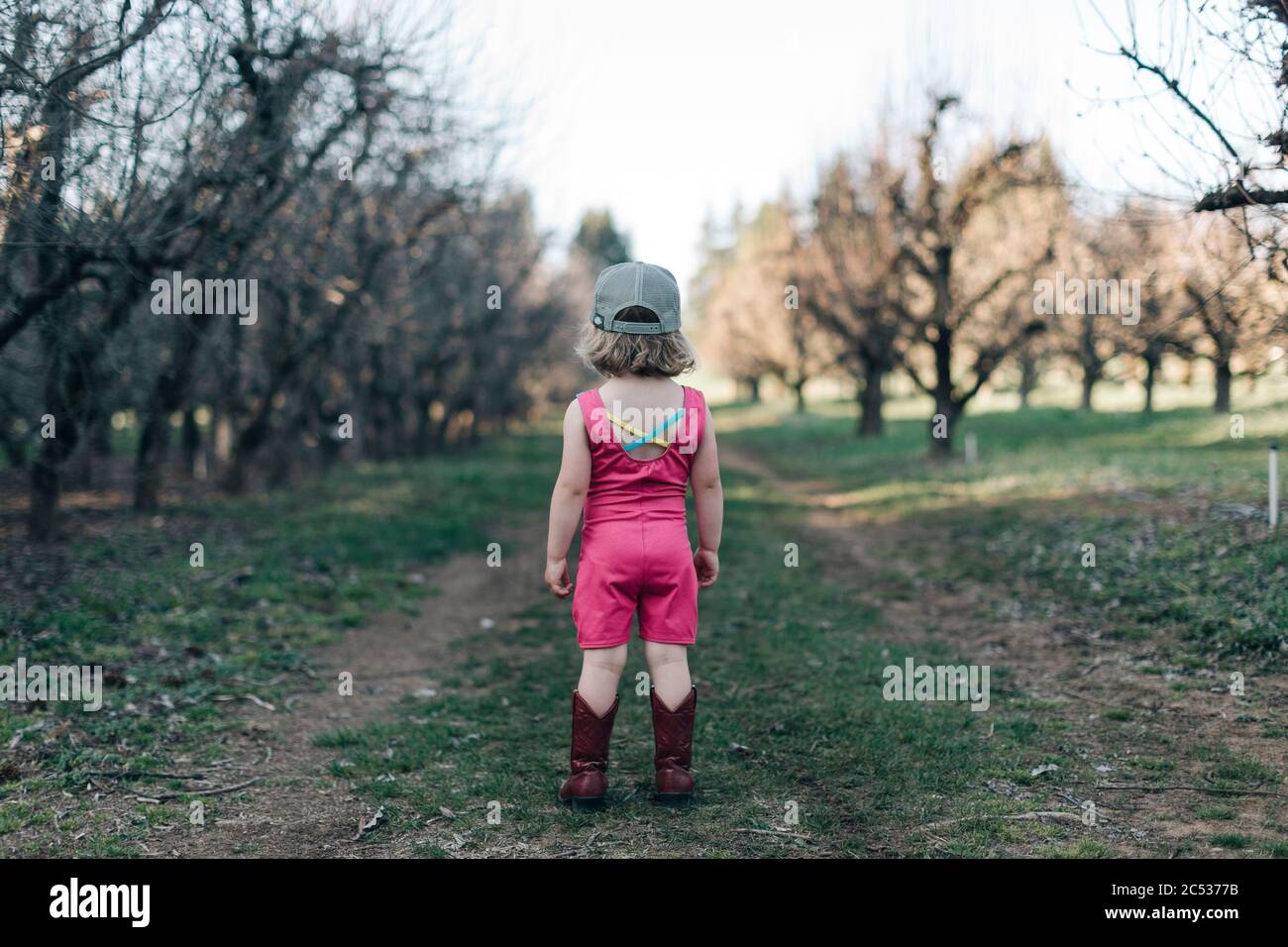 Una niña está de pie en un huerto usando un botín y botas de cowgirl  Fotografía de stock - Alamy