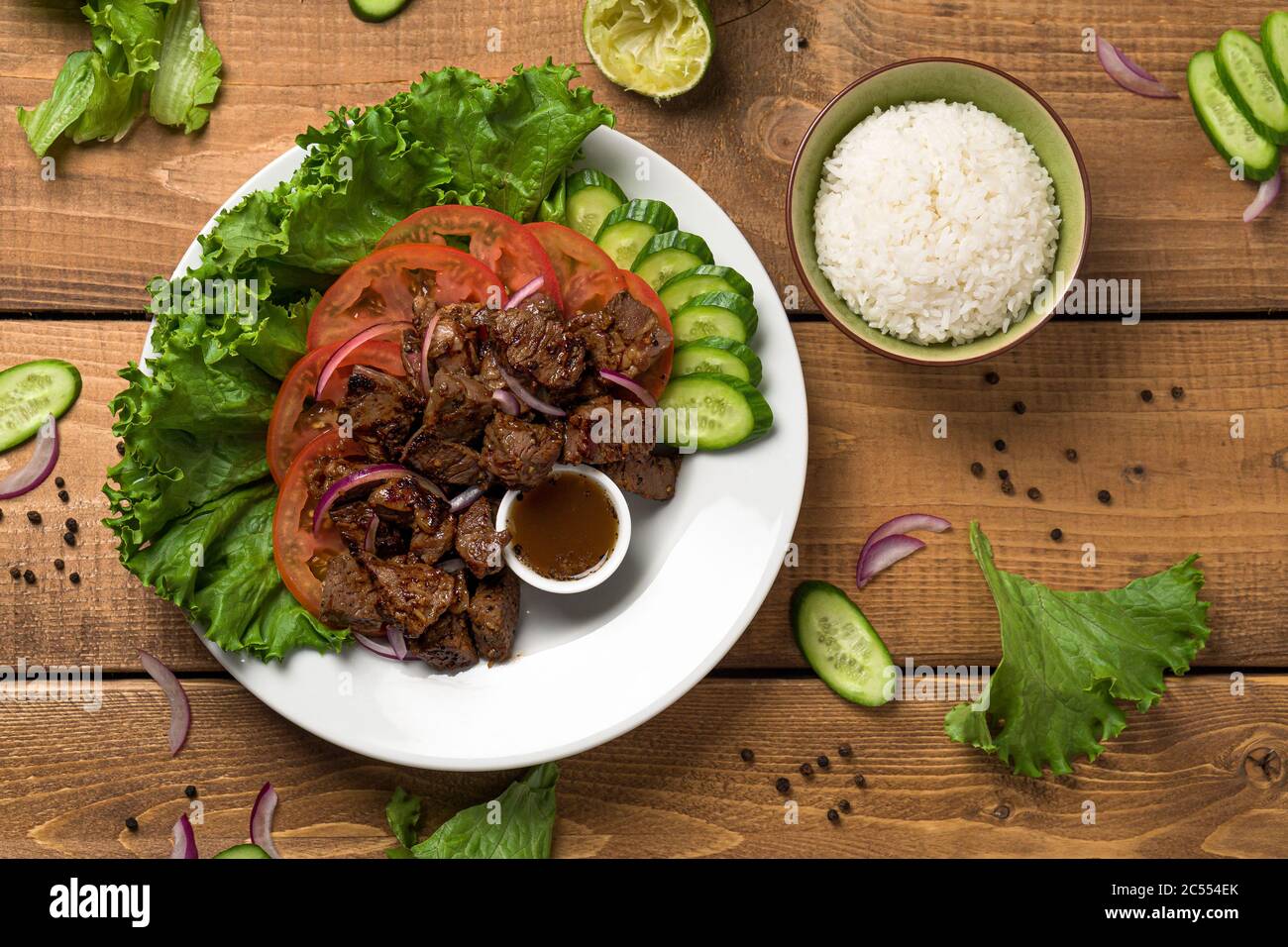 Bo Luc Lac plato sobre fondo de madera. También se llama Lok Lak en camboya  o Betking Beef en América. Sabrosas carnes salteadas marinadas se sirven  con fr Fotografía de stock -
