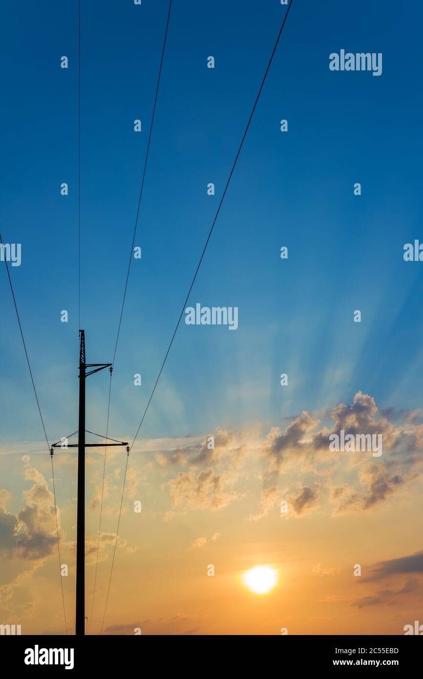 Pilones de alta tensión contra el hermoso cielo con rayos solares. Líneas eléctricas y nubes. Foto de stock