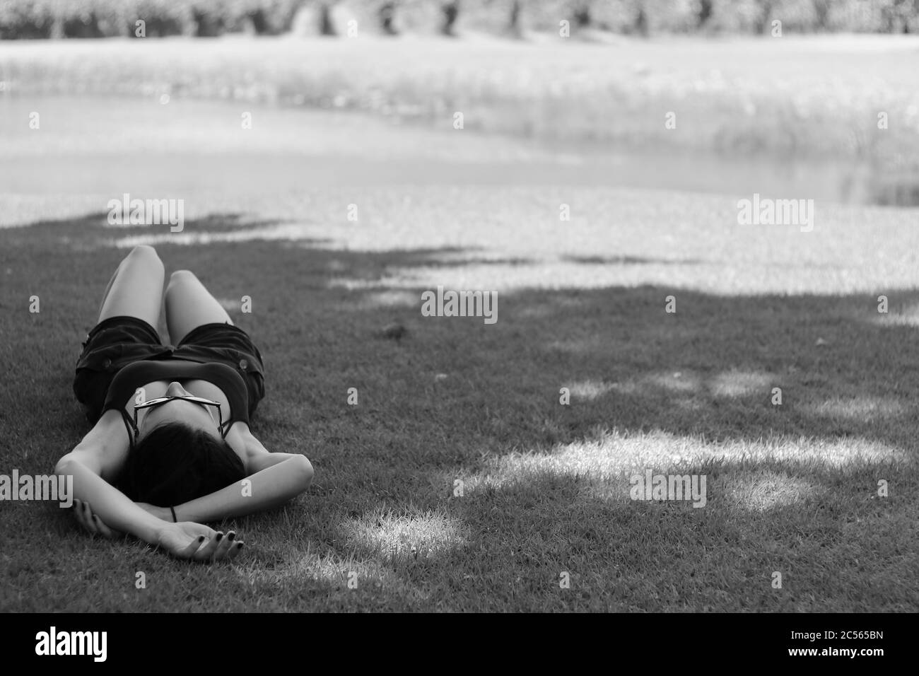 PORT ELIZABETH, SUDÁFRICA - Jun 14, 2020: Una mujer caucásica tomando una siesta en un césped de hierba lejos de otras personas. La nueva imagen de concepto normal. Foto de stock