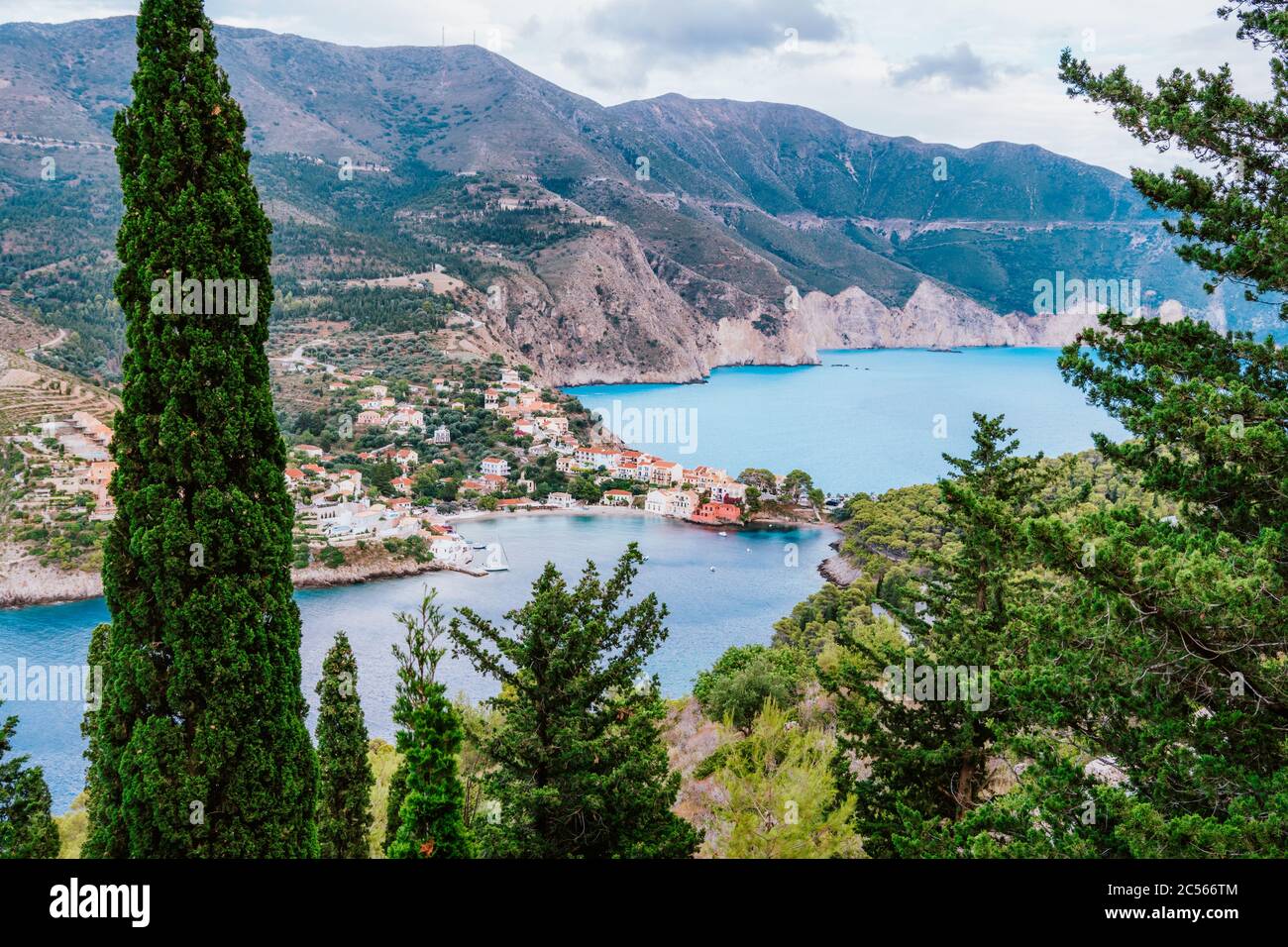 Frourio península y Assos pueblo con hermosa bahía de mar y cipreses árboles en primer plano. Isla de Kefalonia, Grecia. Foto de stock