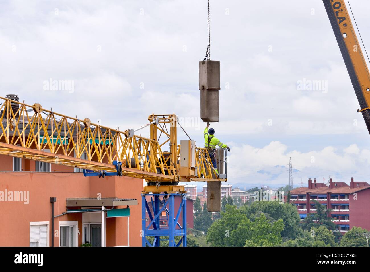 El constructor de grúas coloca pesos de contrapeso de hormigón en la torre del brazo de la pluma Foto de stock