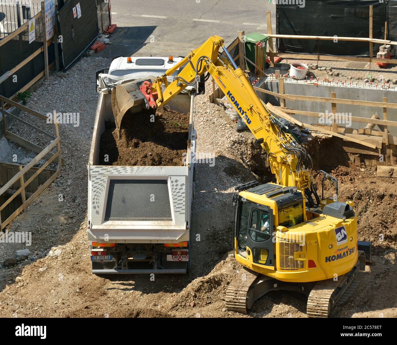 Excavadora hidráulica Komatsu excavando la base de la construcción, descargando el suelo en un camión volquete Foto de stock