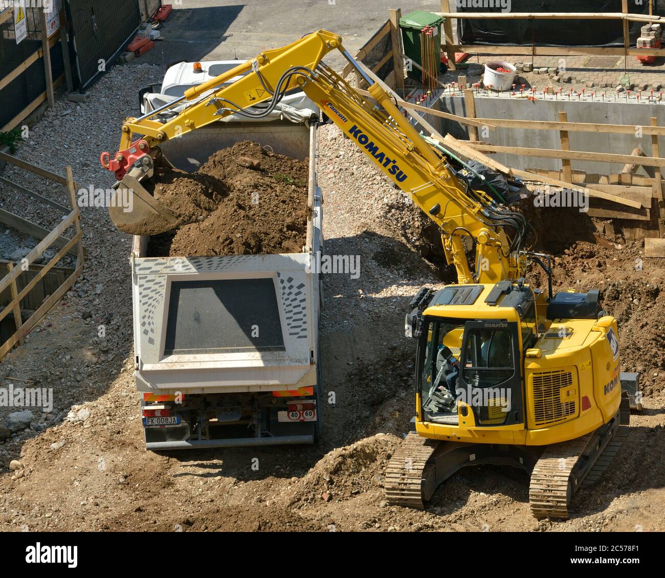 Excavadora hidráulica Komatsu excavando la base de la construcción, descargando el suelo en un camión volquete Foto de stock