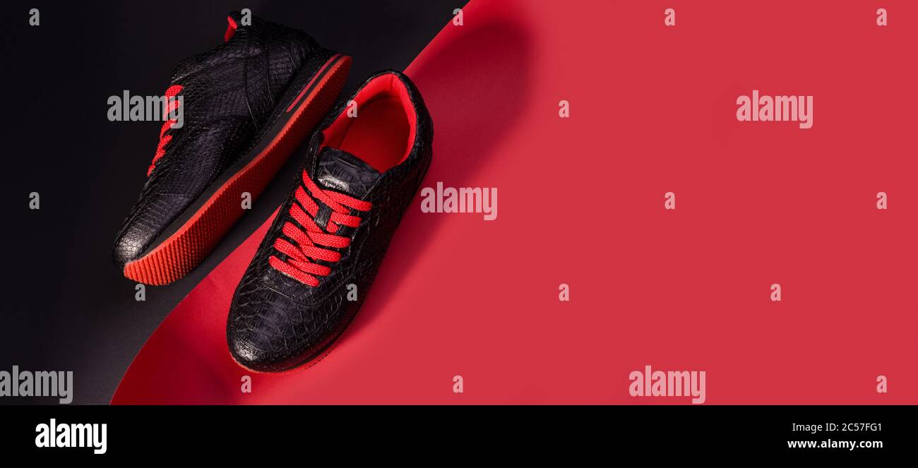 Banner de moda con zapatillas de piel de serpiente. Sneakers negras con  cordones de arranque rojos brillantes sobre fondo negro y rojo Fotografía  de stock - Alamy