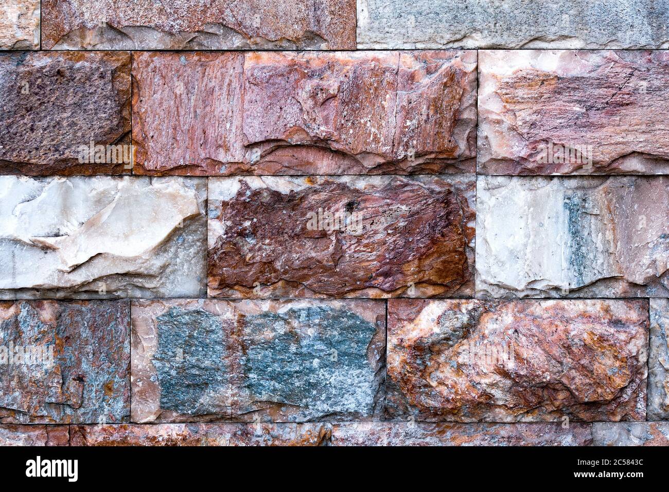 La pared está hecha de mármol texturizado de diferentes colores. Una pared de piedra con una interesante textura de mármol. El mármol de la pared. Foto de stock