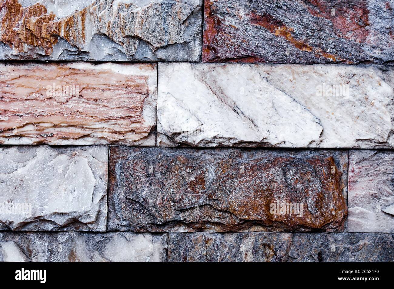 La pared está hecha de mármol texturizado de diferentes colores. Una pared de piedra con una interesante textura de mármol. El mármol de la pared. Foto de stock