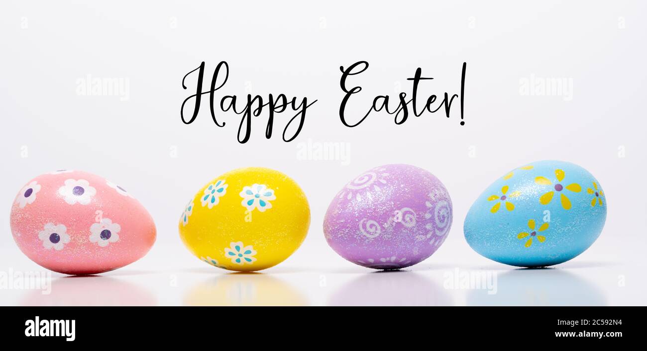 Coloridos huevos de Pascua sobre fondo blanco con saludo Foto de stock