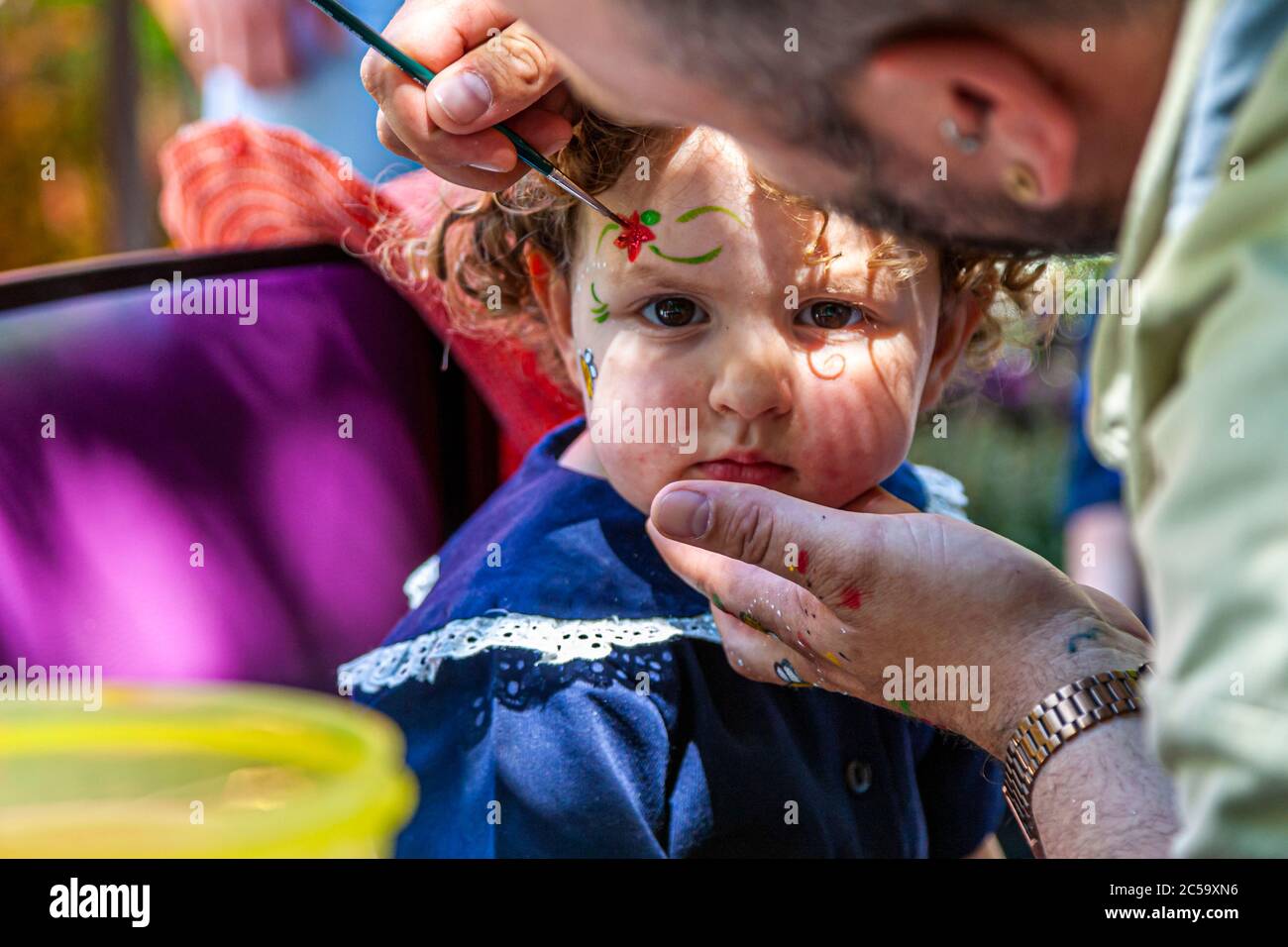 Una niña pequeña se pinta abejas en su cara. Los niños se enfrentan a la pintura en Grevenbroich, Alemania Foto de stock