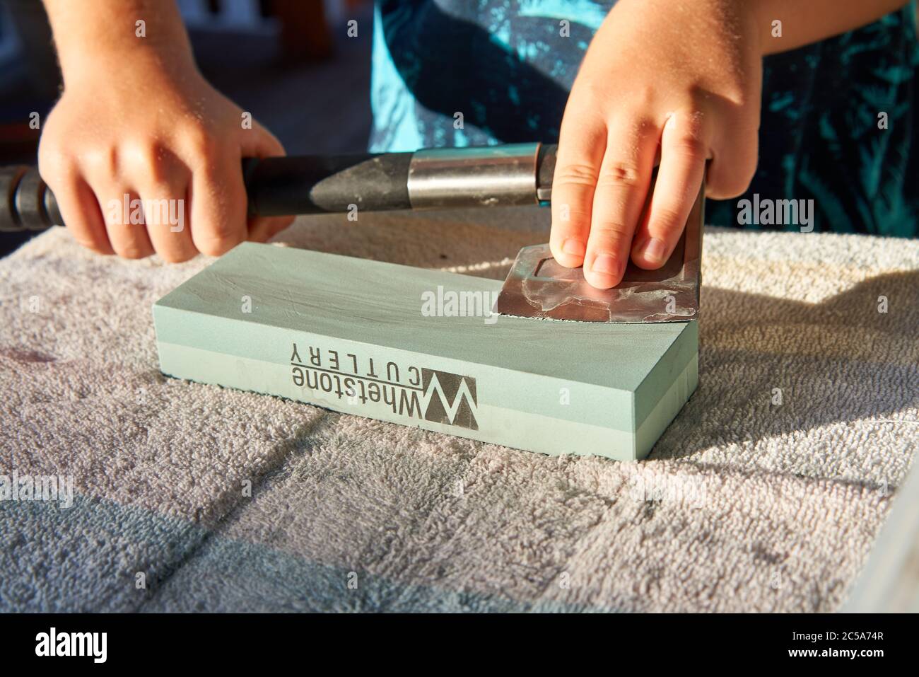 Trabajar con las manos para afilar un hacha de mano sordo usando una piedra  de afilar sobre la mesa Fotografía de stock - Alamy