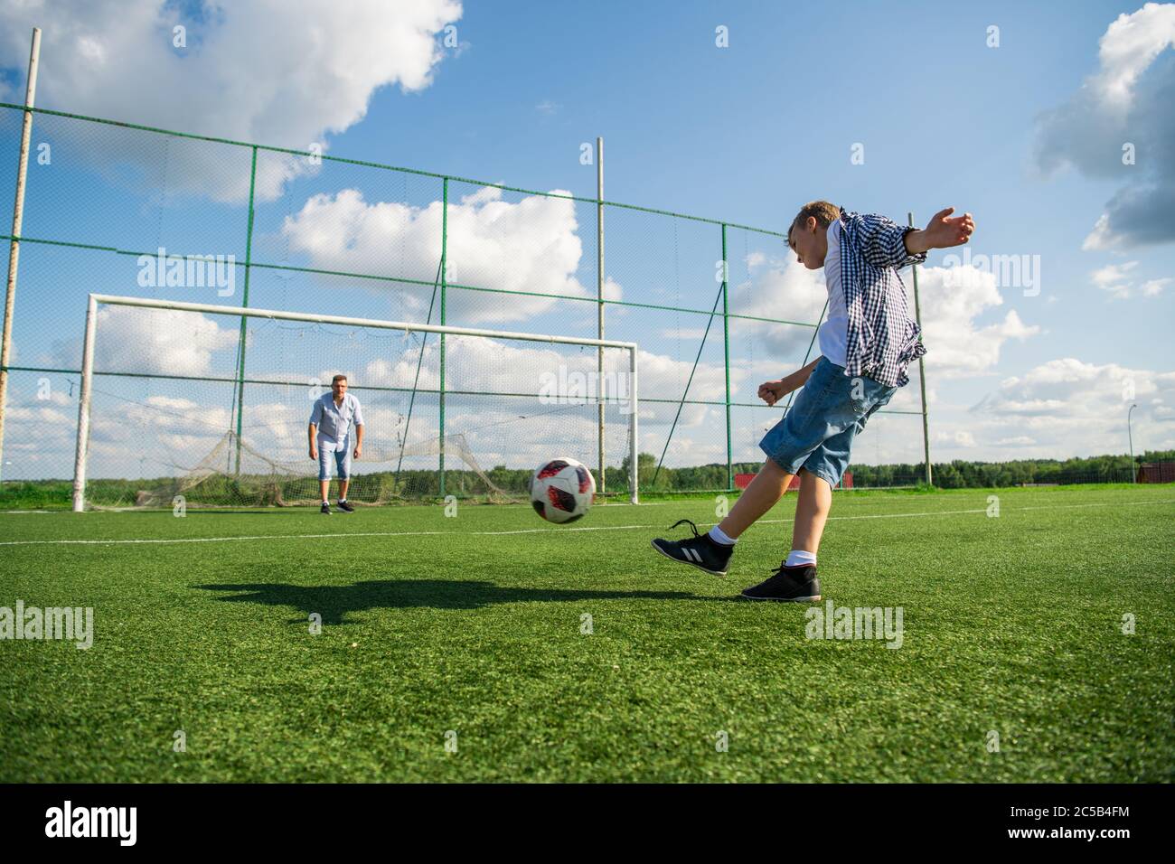 Niño pateando una pena en la meta. Gran angular de bajo ángulo. Foto de stock
