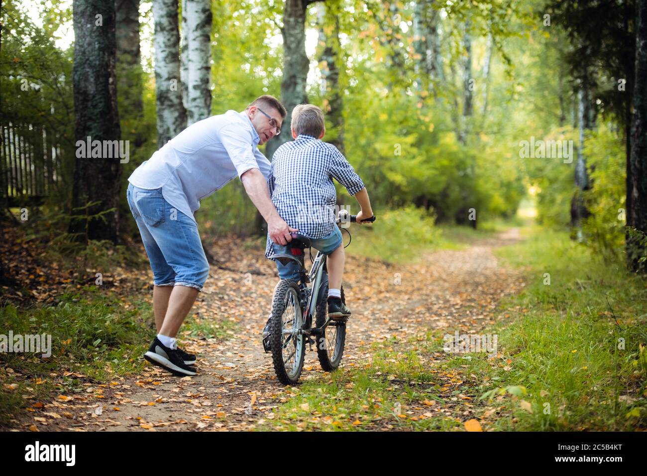 El padre enseña a su hijo a montar en bicicleta Foto de stock