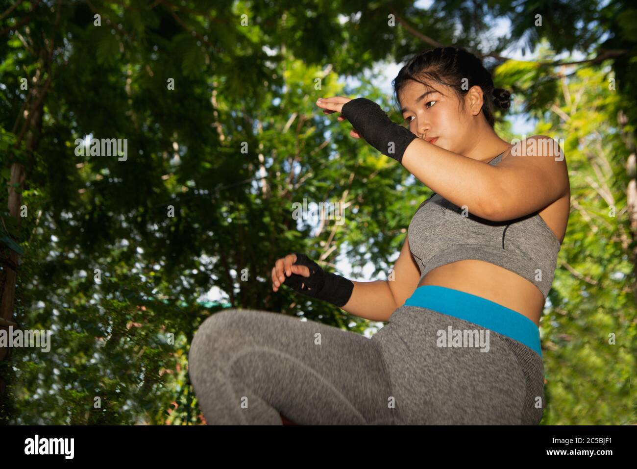 Hermosa niña blanca asiática joven con pelo largo de 20-30 años. Práctica Muay Thai boxing pateando en el club deportivo. Foto de stock