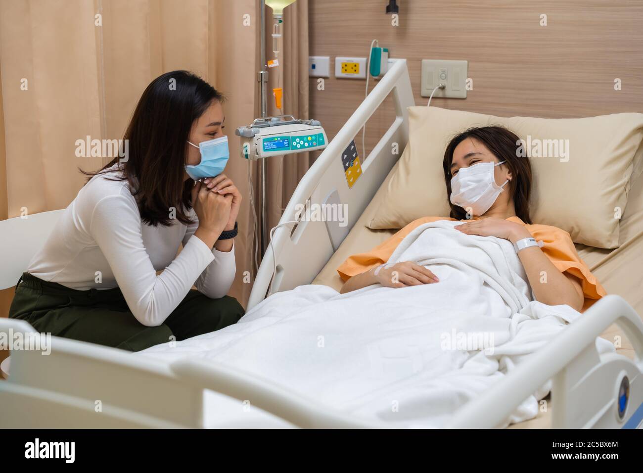 mujer que visita y cuida a una paciente en una cama en el hospital. las  personas deben usar máscara médica para prevenir la pandemia del  coronavirus (covid-19 Fotografía de stock - Alamy