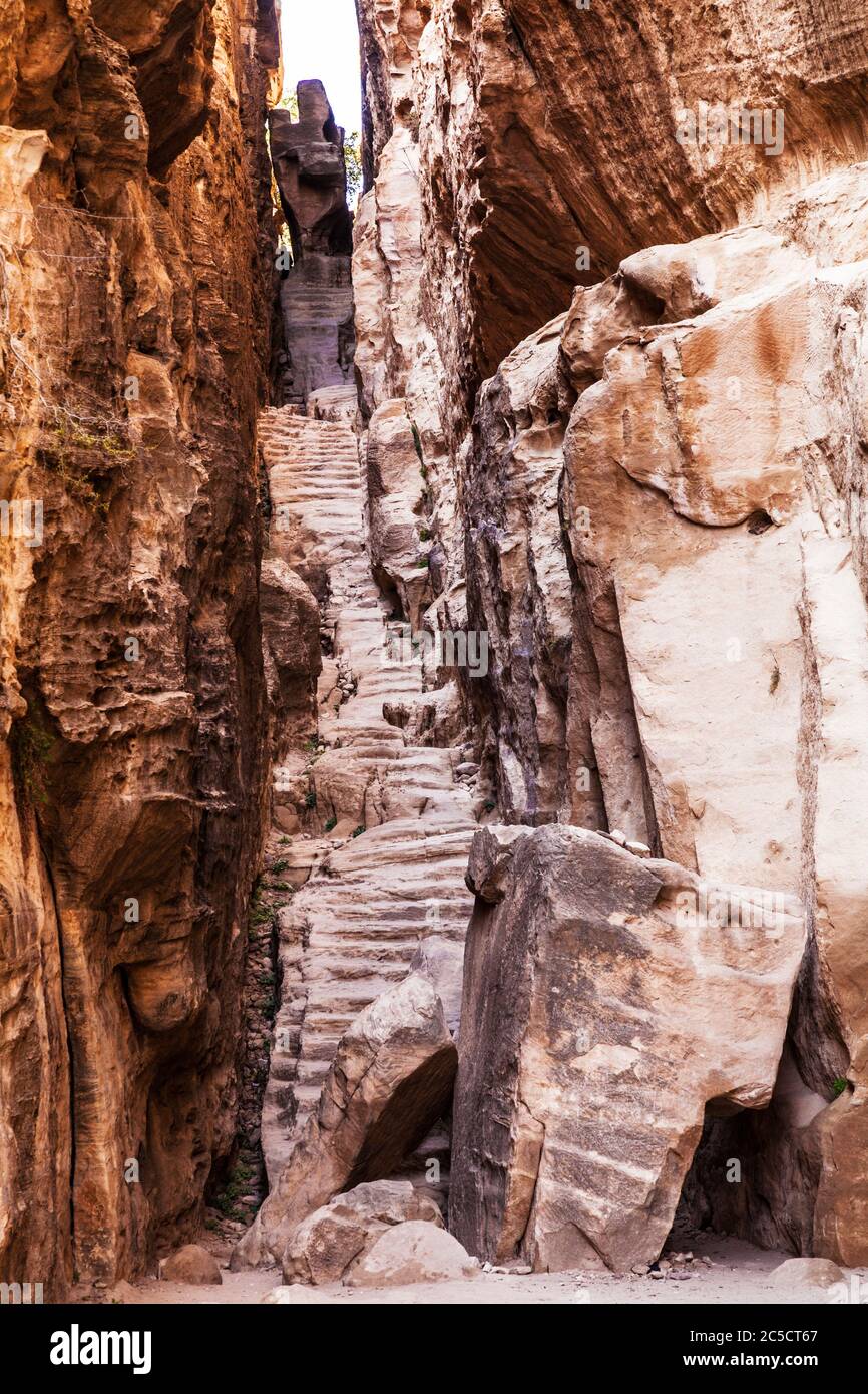 Los pasos recortan una estrecha brecha en el cañón de Siq al-Barid o la pequeña Petra en Jordania Foto de stock