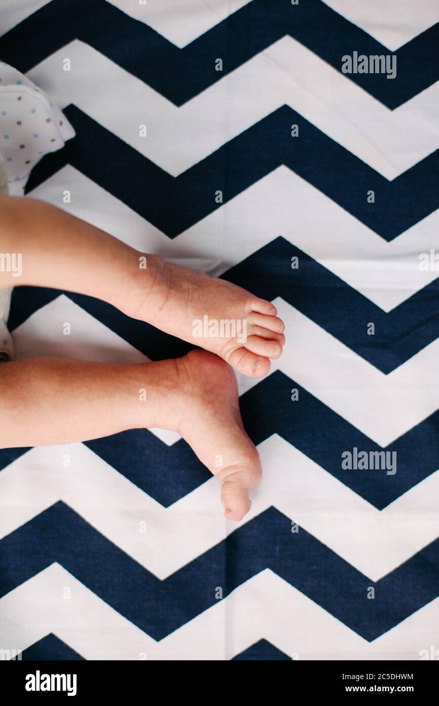 Bebé de 4 meses de edad sentado con los pies descalzos sobre una alfombra.  Juguetes en primer plano Fotografía de stock - Alamy