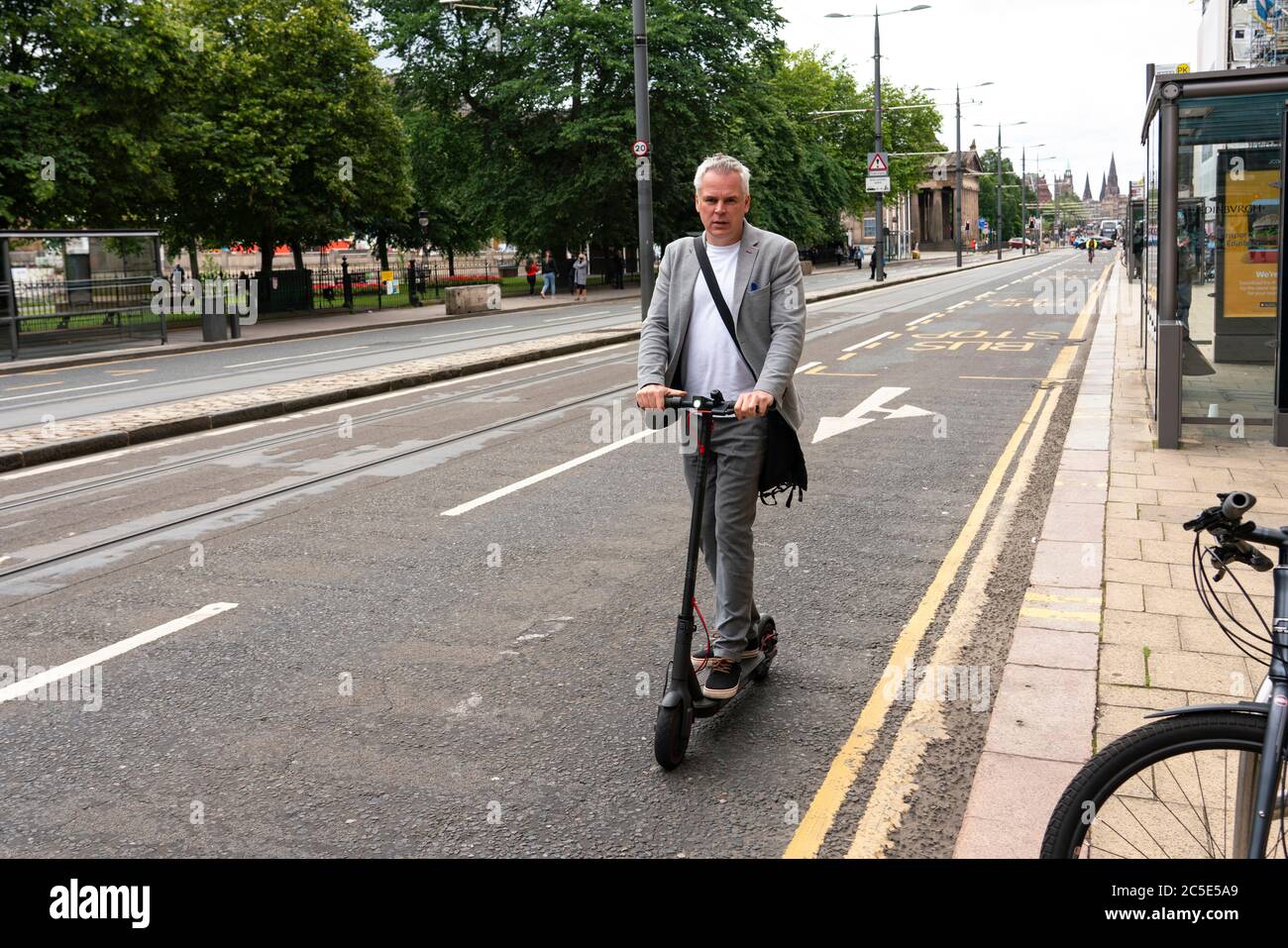 Edimburgo, Escocia, Reino Unido. 2 de julio de 2020. Un hombre que monta una scooter eléctrica para viajar por Princes Street en Edimburgo. El gobierno permitirá este mes ensayos en carreteras públicas en Inglaterra de scooters eléctricos. Actualmente su uso está prohibido. Ensayos no programados en Escocia. Iain Masterton/Alamy Live News Foto de stock