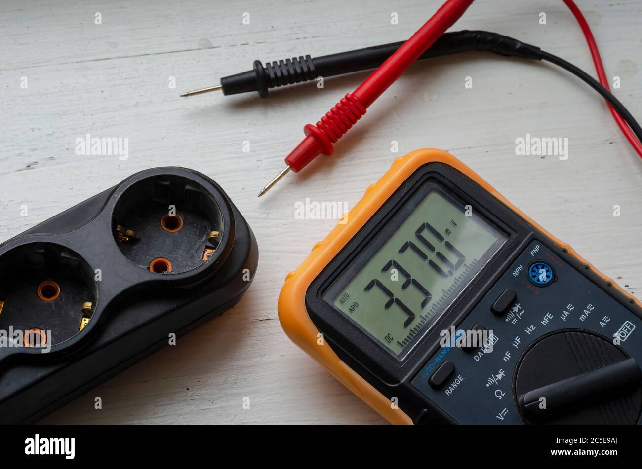 Multímetro y divisor eléctrico sobre fondo de madera blanco. Medición