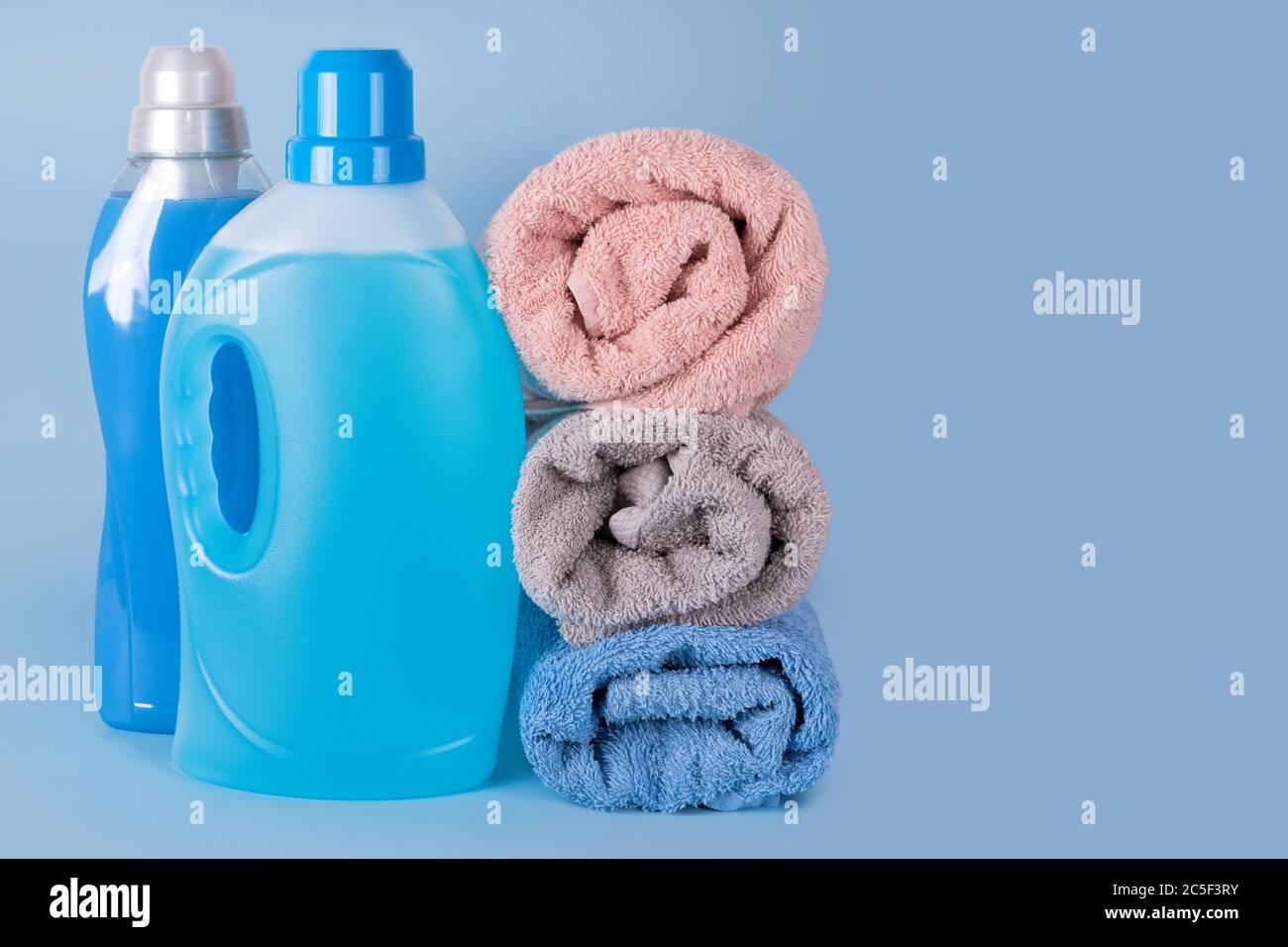 Botellas de detergente y suavizante con toallas limpias sobre fondo azul.  Envases de productos de limpieza, productos químicos domésticos. Detergente  líquido Fotografía de stock - Alamy