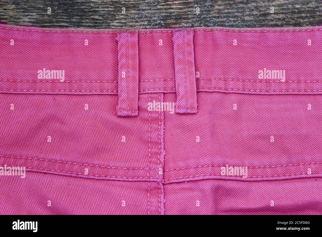 La parte posterior de los pantalones vaqueros de color rosa. Pantalones  vaqueros para hombre sobre una superficie de madera. Fondo denim Fotografía  de stock - Alamy