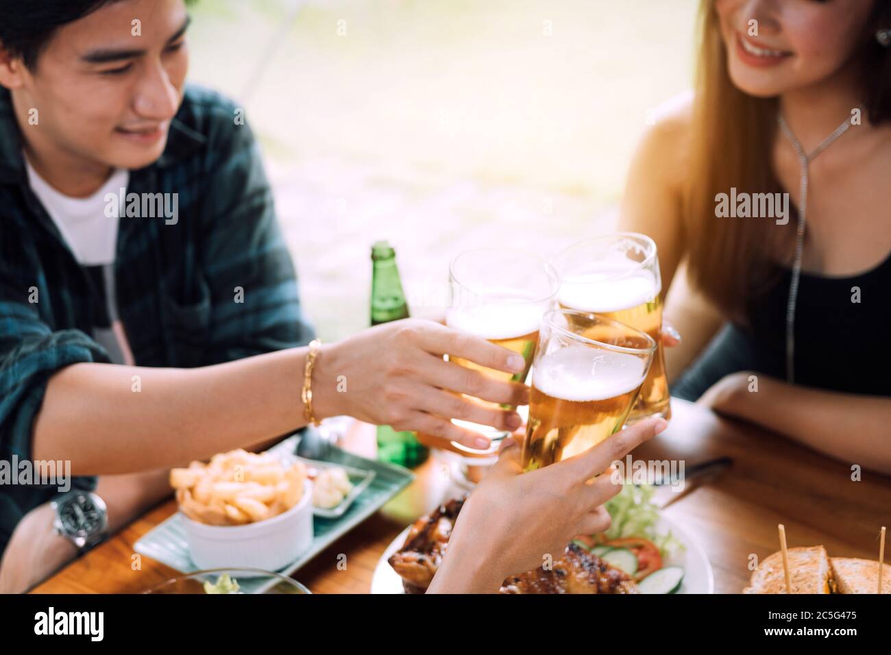 Teeneger amigos asiáticos clinking gafas mientras disfruta de una cena en un restaurante. Foto de stock