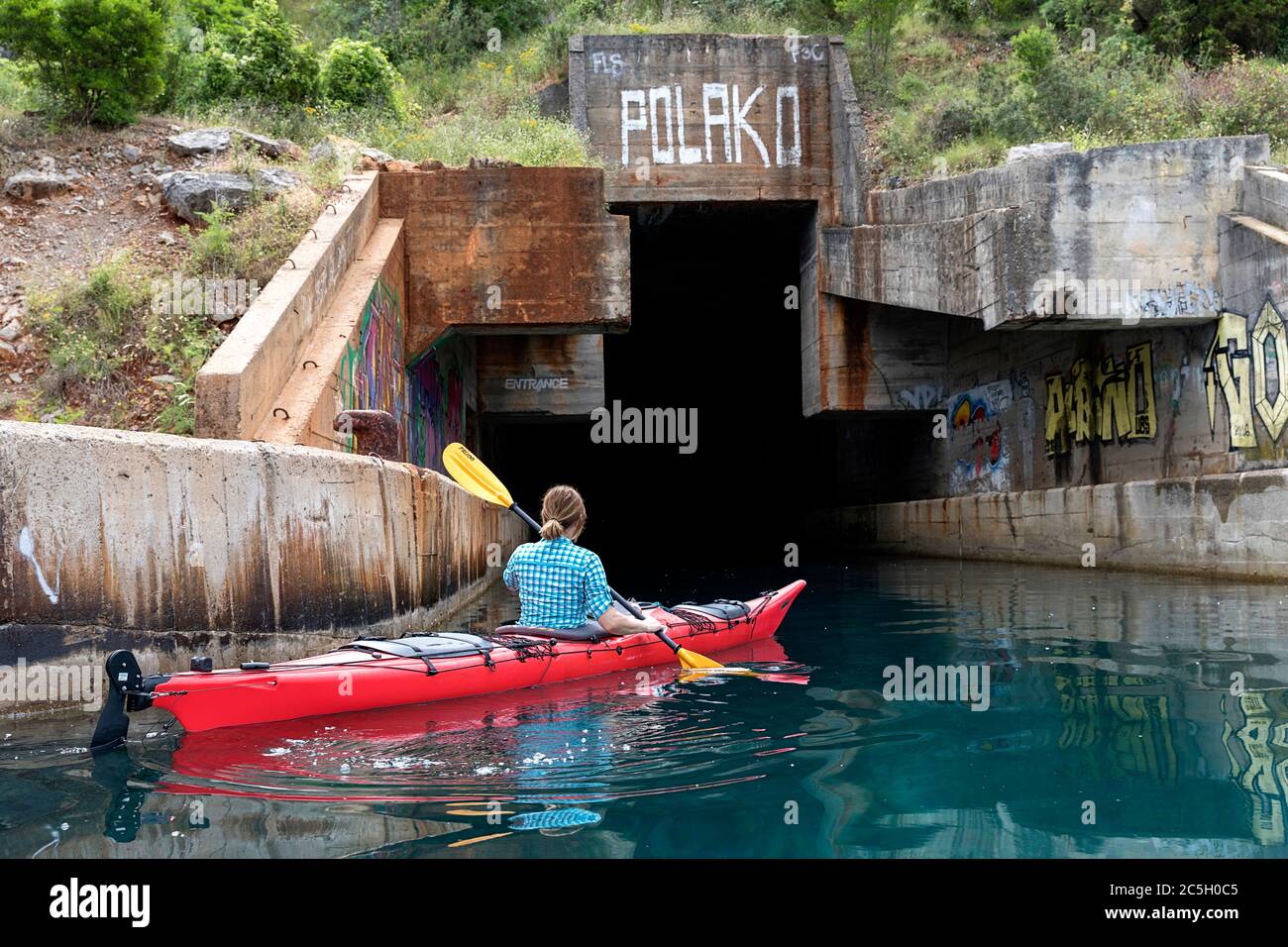 Mujer kayak en ex Yugoslavia submarino secreto salida de la base de montaña, península de Lustica, Montenegro Foto de stock