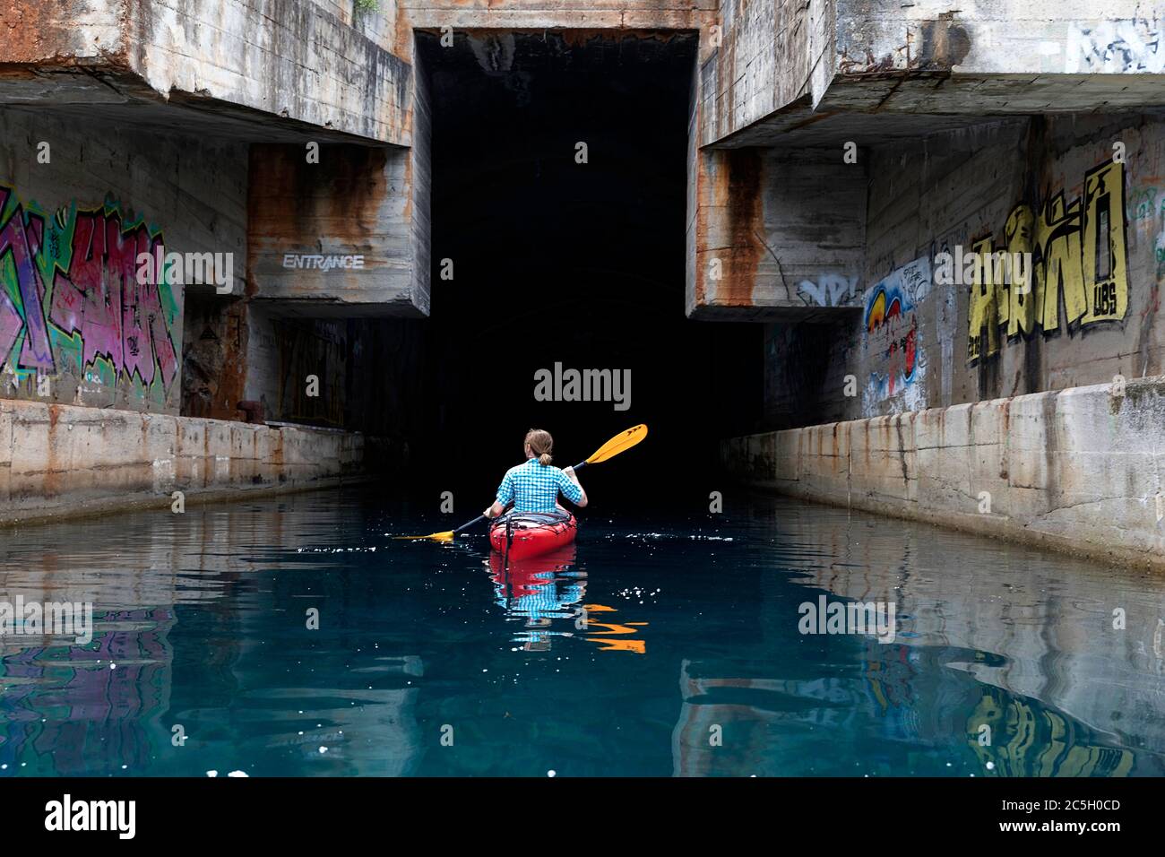Mujer kayak en ex Yugoslavia submarino secreto salida de la base de montaña, península de Lustica, Montenegro Foto de stock