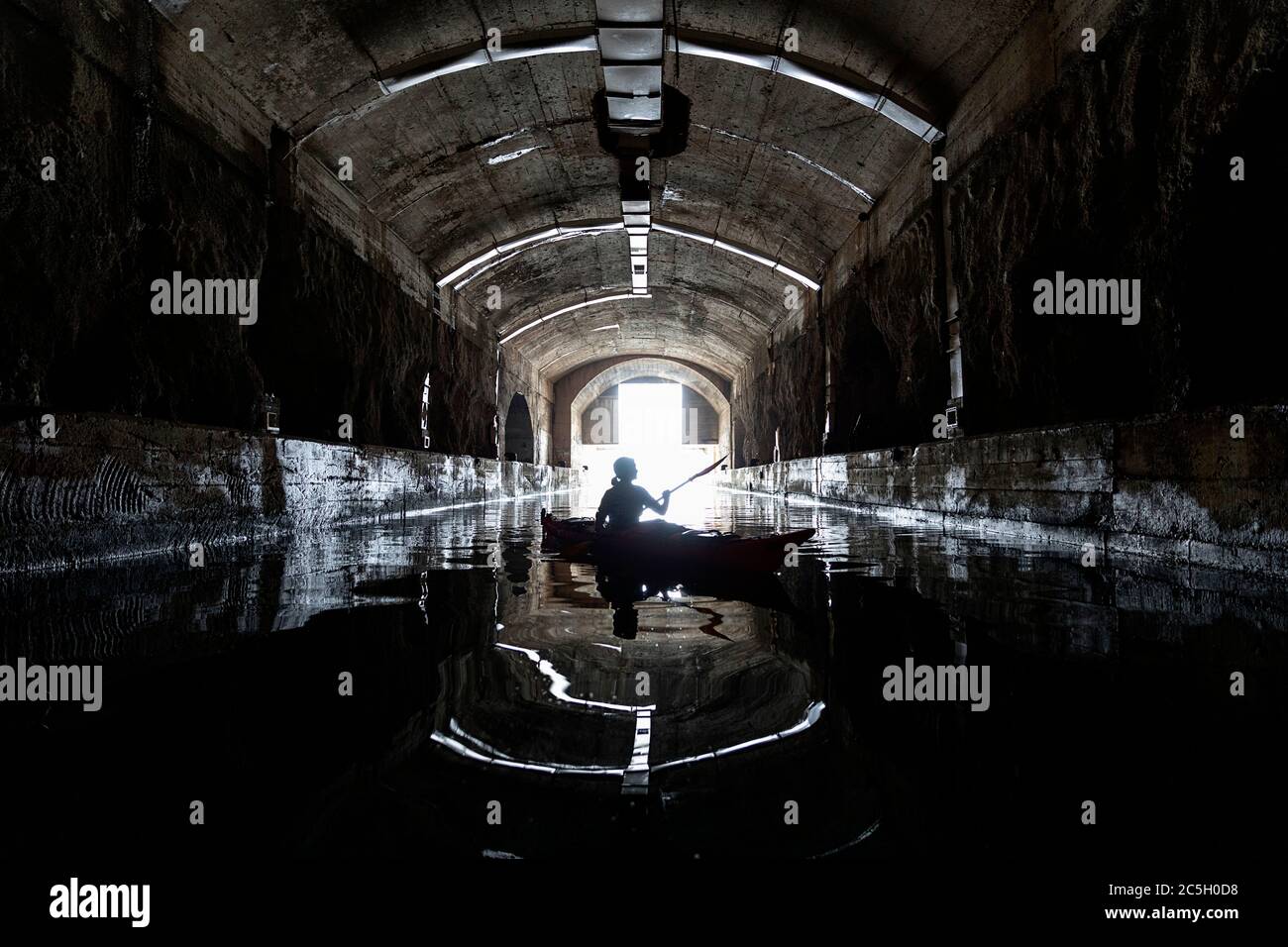 Mujer kayak en ex Yugoslavia submarino secreto salida de la base de montaña, península de Lustica, Montenegro Foto de stock