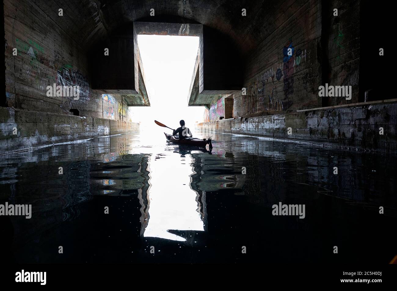Mujer kayak en ex Yugoslavia submarino secreto salida de la base de montaña, península de Lustica, Montenegro Foto de stock