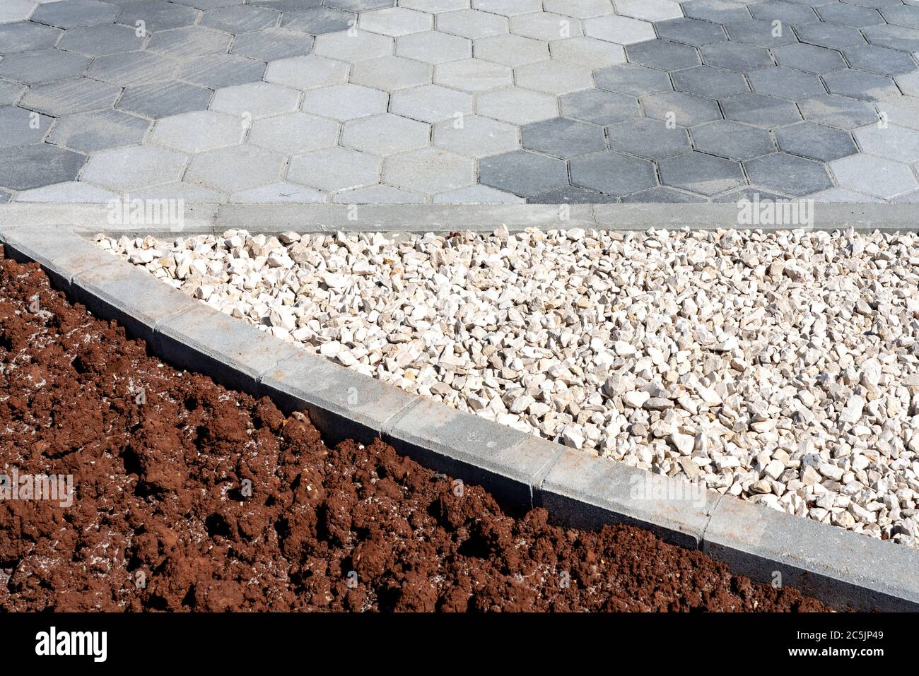 Camino de adoquín hexagonal gris dividido con guijarros y suelo para  posterior siembra. Planificación urbana Fotografía de stock - Alamy