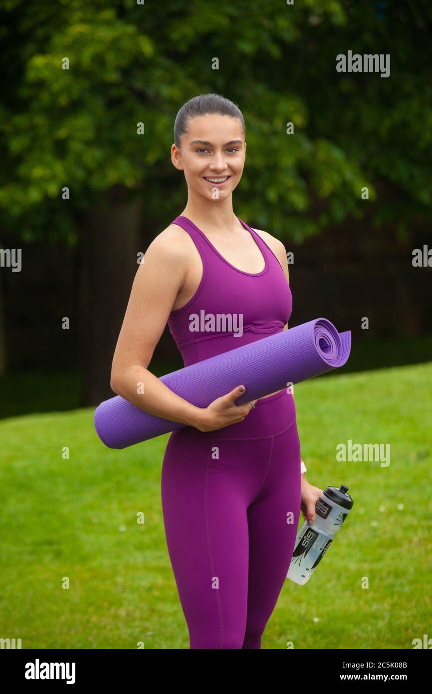 Retrato de una joven atlética en leggings y sujetador deportivo con una alfombra de ejercicio Foto de stock