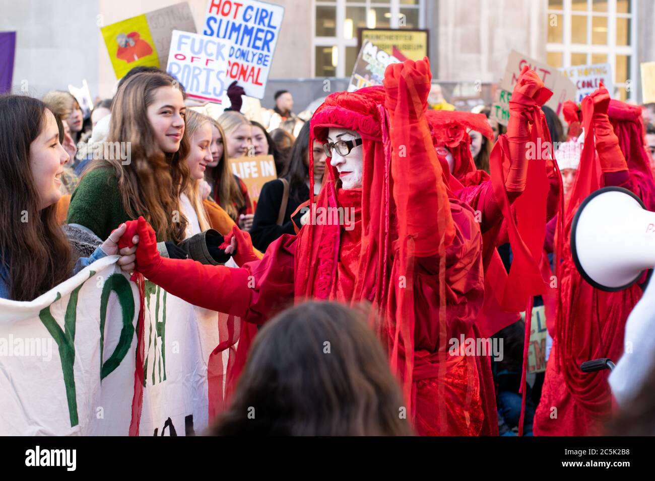 Ataque climático global en la Plaza de San Pedro, Manchester, Reino Unido. Extinción rebelión los rebeldes rojos de circo invisibles se mantienen en manos de los manifestantes mientras caminan Foto de stock
