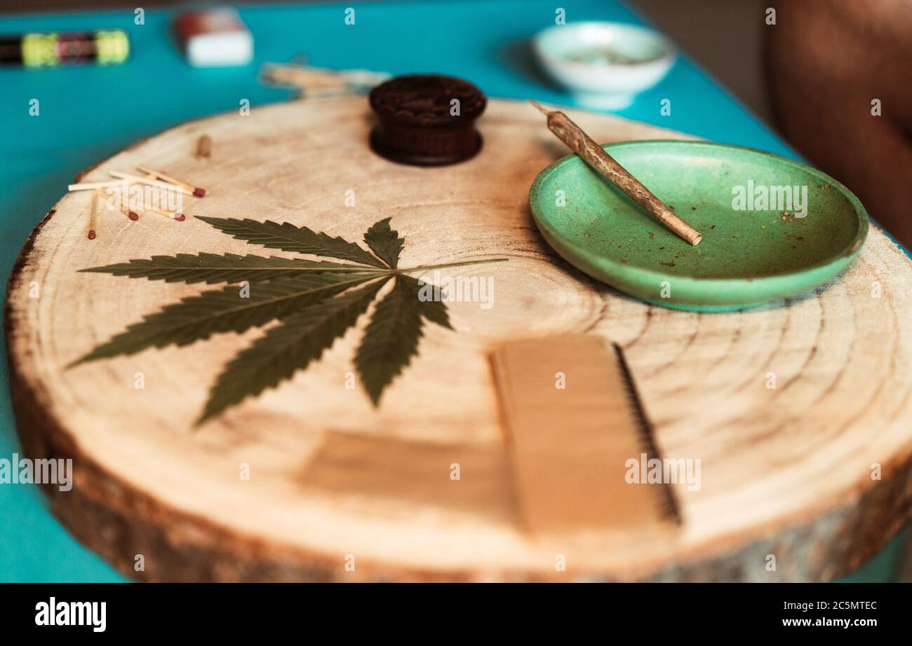 Molinillo con articulación de cannabis, hoja seca de maleza sobre mesa de madera - enfoque en filtro de tubería Foto de stock