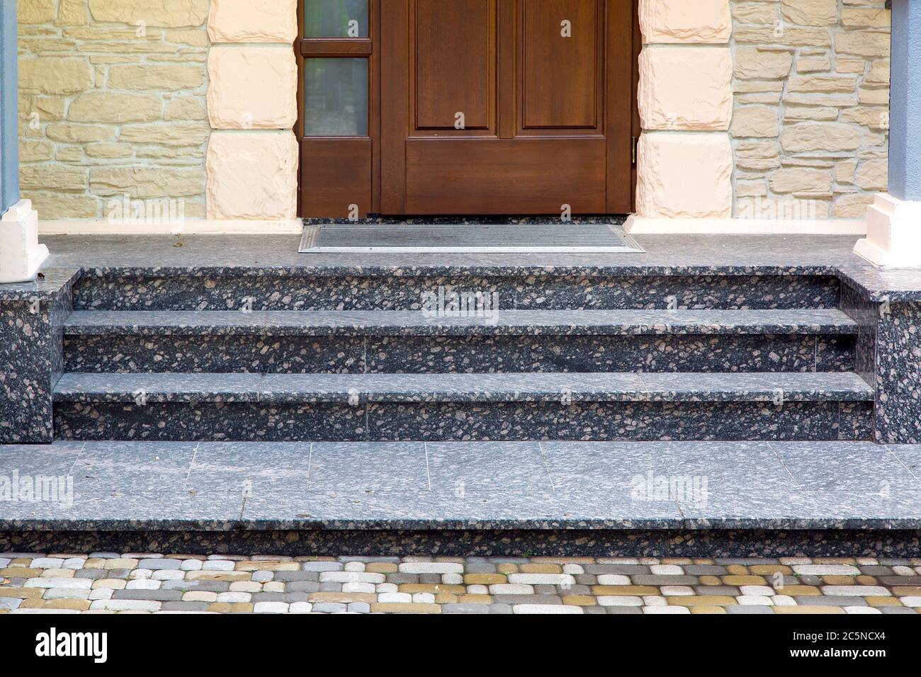 umbral de entrada con escalones de mármol a una puerta de madera con una  alfombra de goma y una fachada de piedra y rusticiación Fotografía de stock  - Alamy