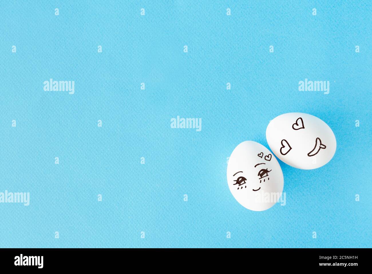 Pareja huevos con el concepto de cara feliz por amor, fondo azul con espacio vacío Foto de stock