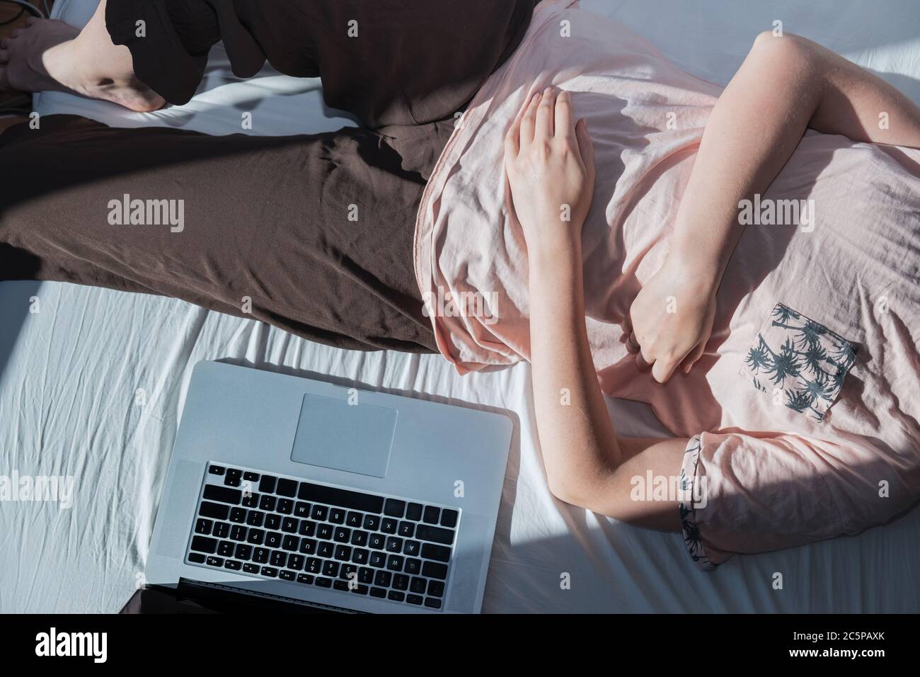 Dilación, descanso del trabajo: Una mujer descansa en la cama junto a una computadora. Concepto de trabajo remoto, no ser productivo, ser trabajo perezoso Foto de stock
