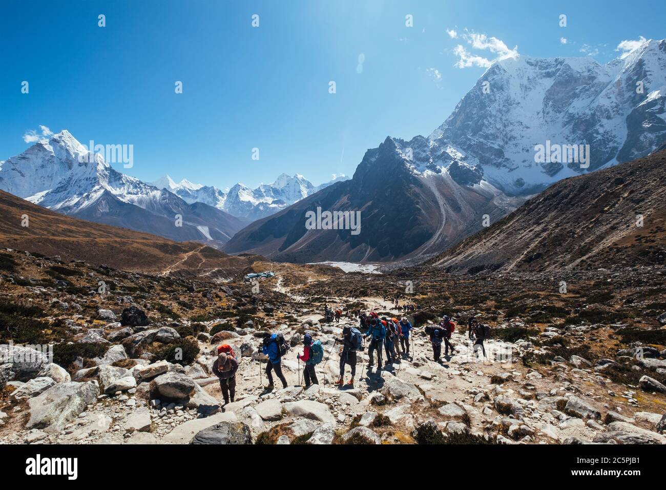 Grandes miembros de la expedición grouon Everest base Camp ruta de senderismo cerca de Dughla 4620m. Backpackers usando bastones de senderismo y pasando por el valle con Ama Foto de stock