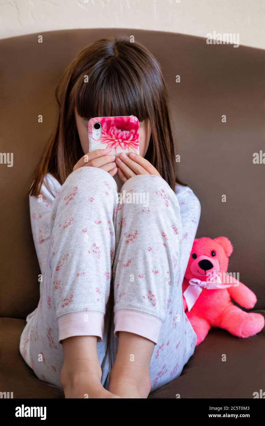 Niña de ocho años jugando en un teléfono inteligente Foto de stock