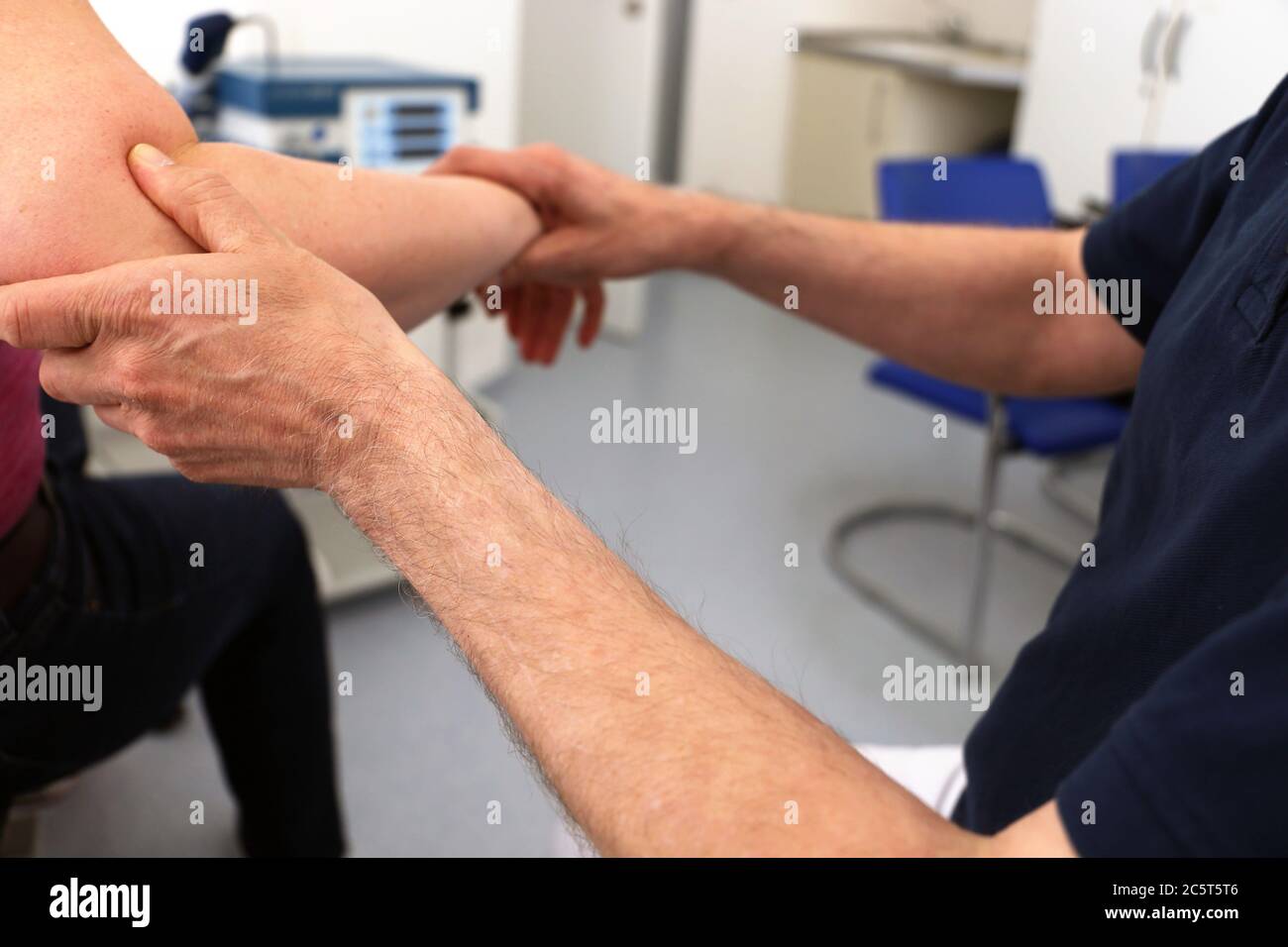Orthopäde untersucht den Ellenbogen einer Patientin Foto de stock